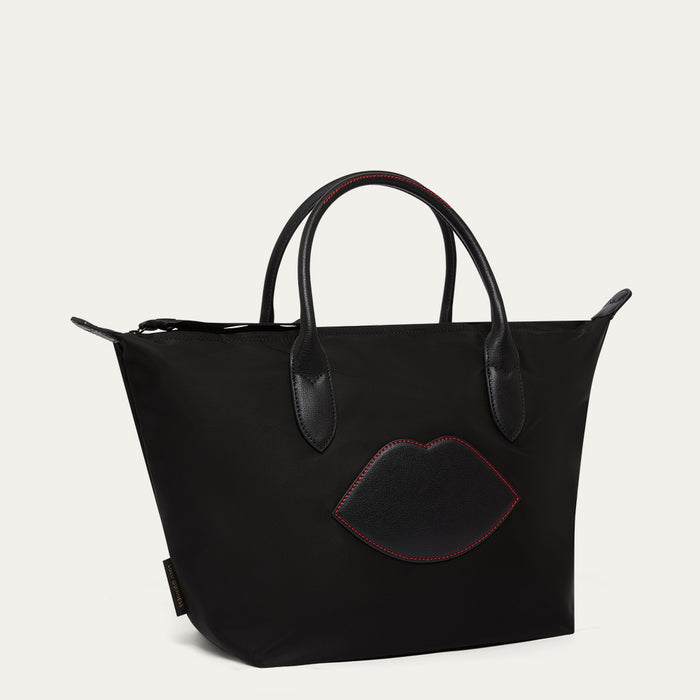 Black handbag with a lip-shaped patch on a light gray background