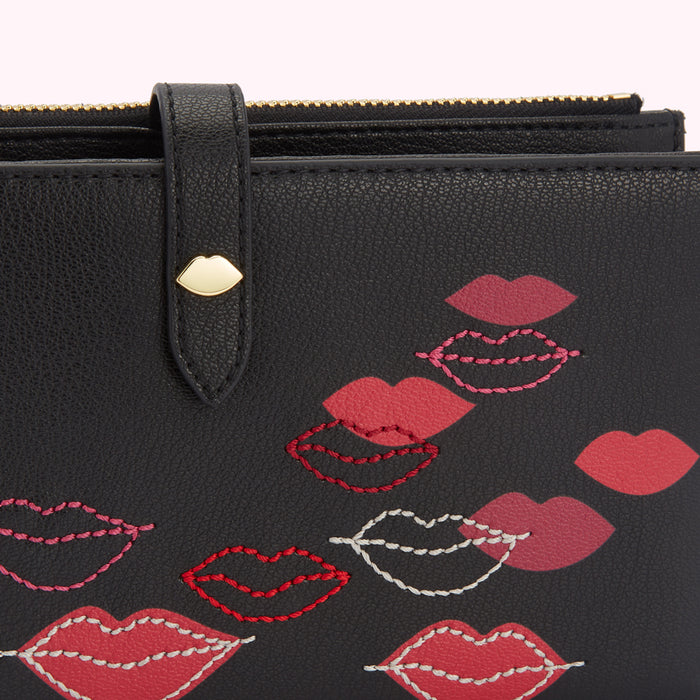 Close-up of a black leather wallet with embroidered lips.