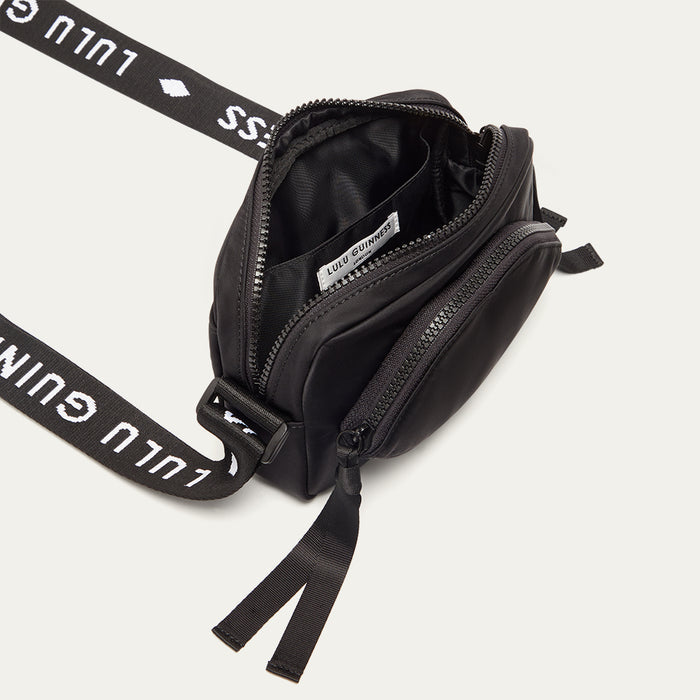 Black crossbody bag with a branded 'Lulu Guinness' strap open revealing a black lining on a white background