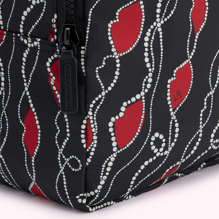 Close-up of a black Lulu Guinness makeup bag featuring a red lips and pearls design.