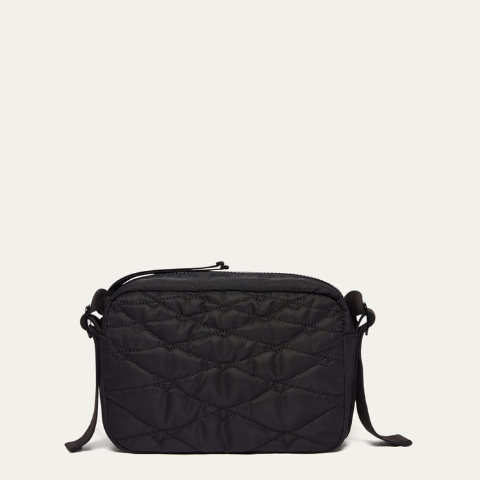 Black quilted crossbody bag on a light beige background