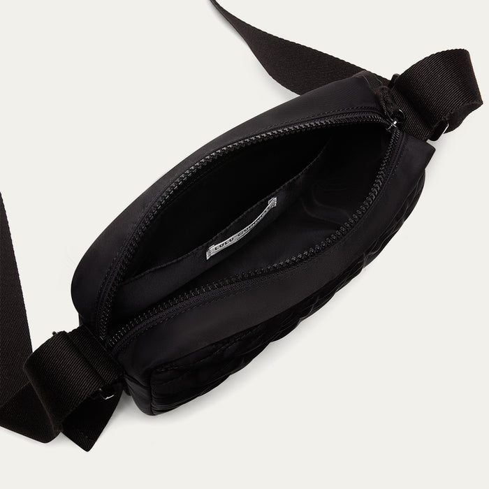 Black quilted crossbody bag open revealing the black lining on a white background