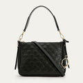 Black quilted handbag with gold accents on a light gray background
