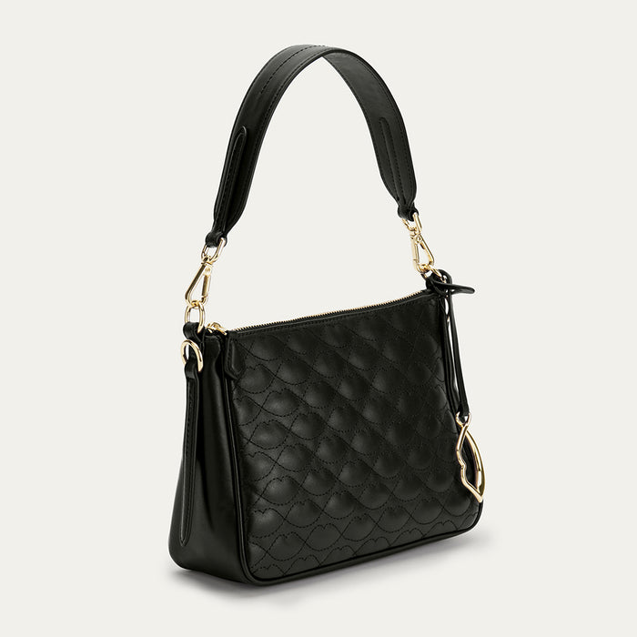 Black quilted handbag with gold accents on a light gray background