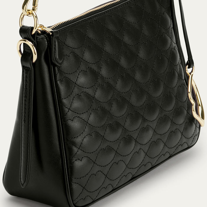 Black quilted handbag with gold accents on a light gray background