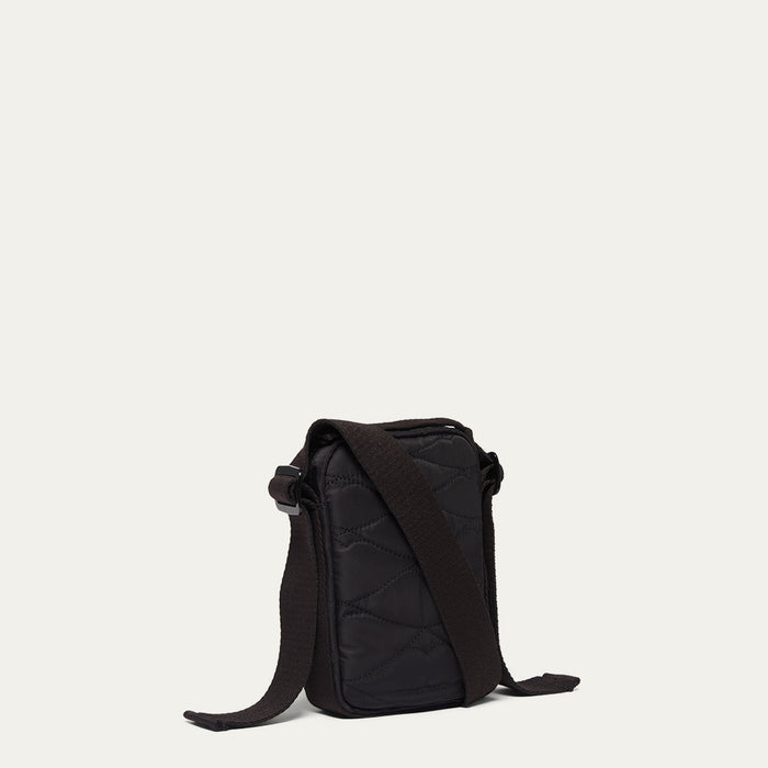 Black quilted crossbody bag on a light beige background