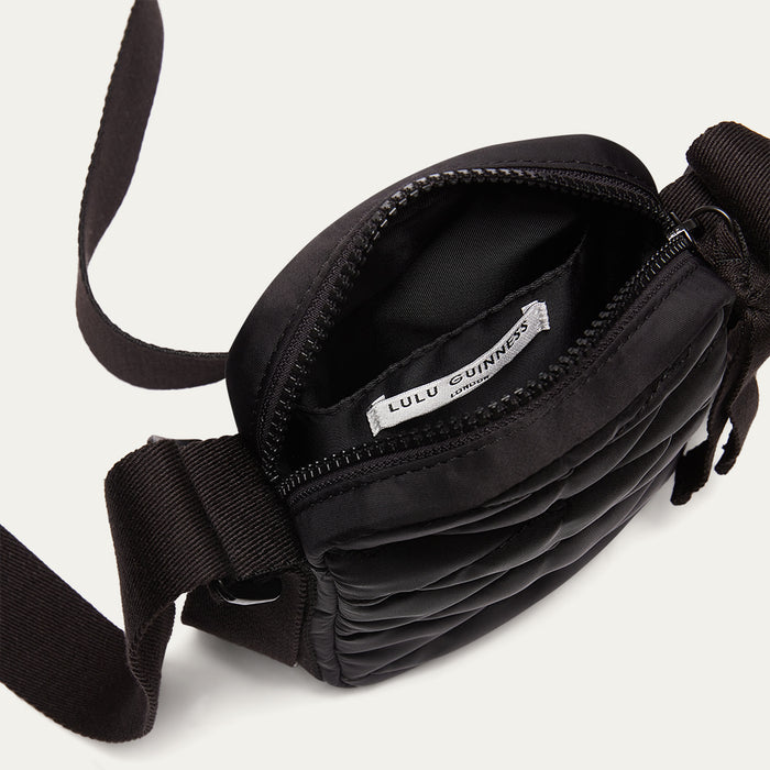 Black crossbody bag open with visible brand label on a light gray background