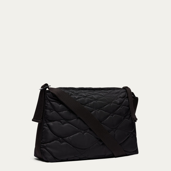 Black quilted shoulder bag on a light beige background