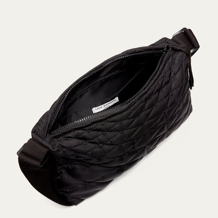 Black quilted shoulder bag open to reveal the lining on a light gray background