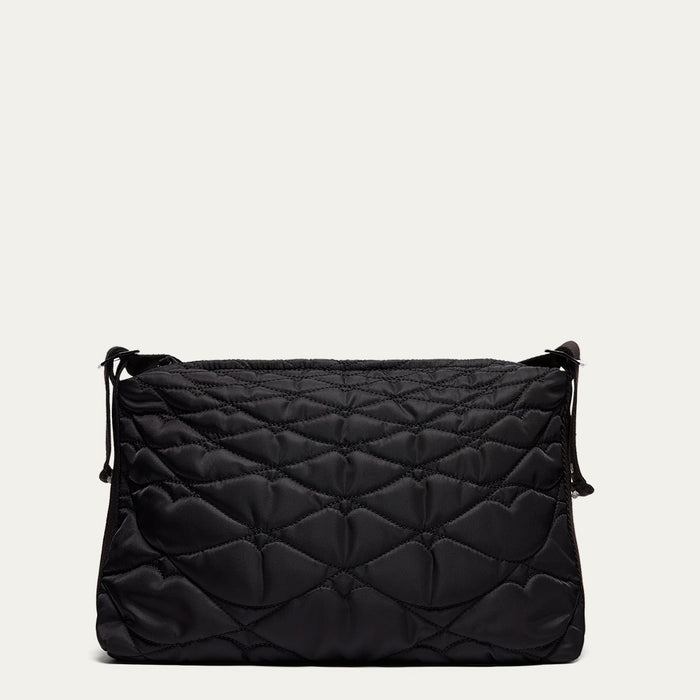 Black quilted shoulder bag on a light beige background