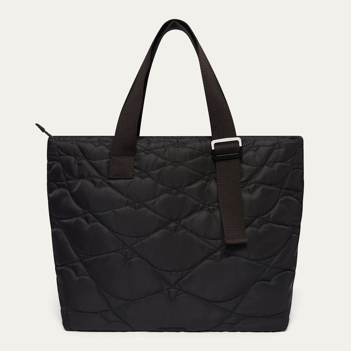 Black quilted tote bag with woven straps on a light gray background