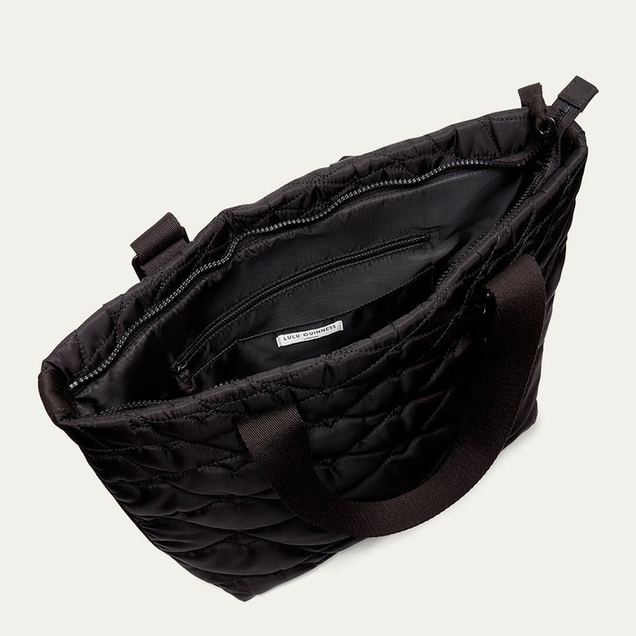 Black quilted tote bag open to reveal a inside pocket on a light gray background