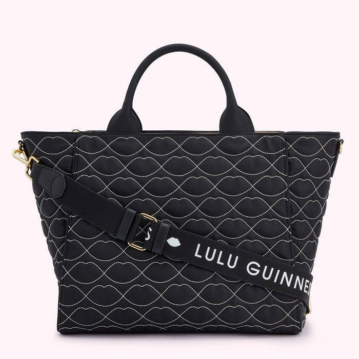 Black quilted tote bag with a white lip pattern and a removable shoulder strap that says "Lulu Guinness".