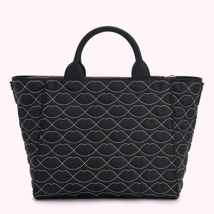 Black quilted tote bag with a lip print pattern.