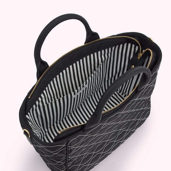 Black quilted handbag with black and white striped interior lining and gold zippers.