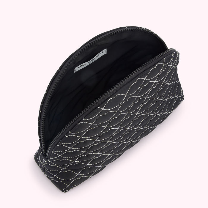 Black quilted makeup bag by Lulu Guinness, open to reveal the interior.