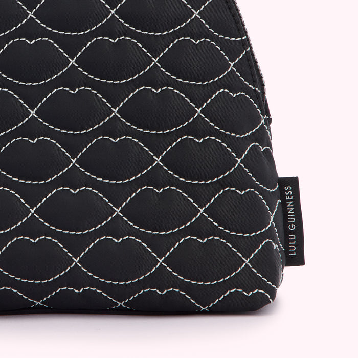 Close-up of a black Lulu Guinness makeup bag with a quilted lip design.