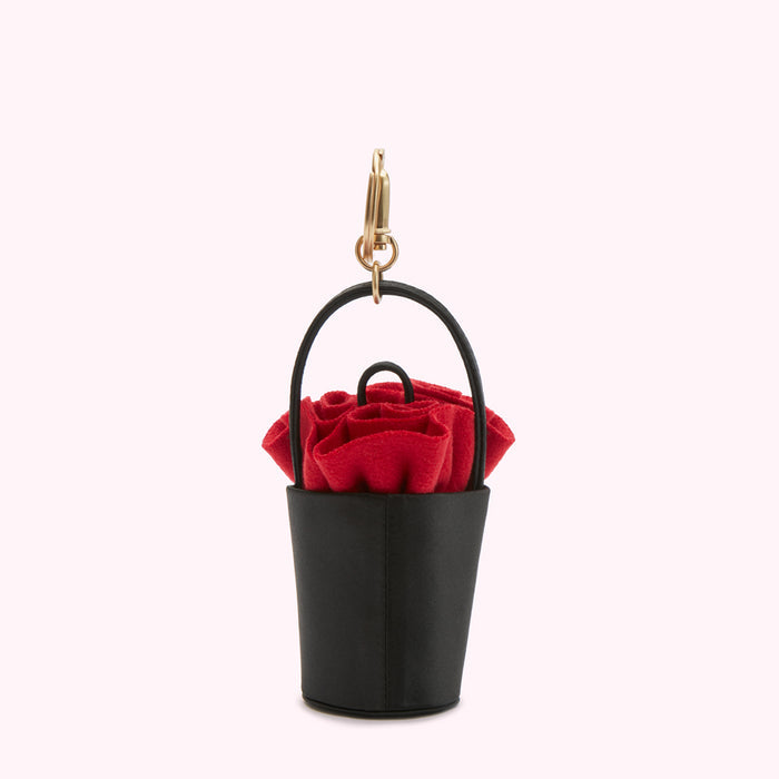 Black bucket bag keychain with a red rose detail.
