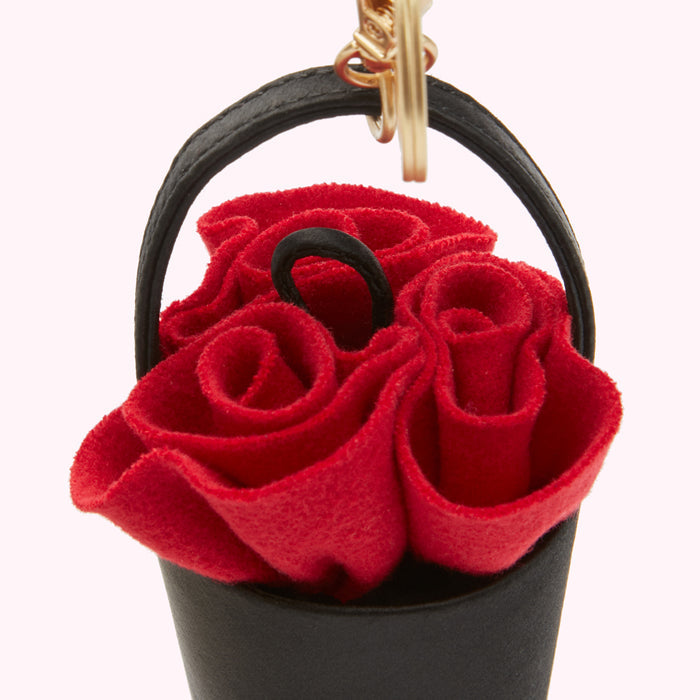 Close-up of a red felt rose bouquet keychain in a black leather bucket.