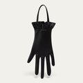 Black satin hand-shaped bag with ruffled cuff on a light gray background