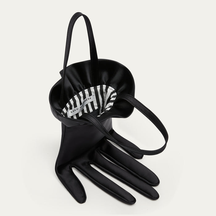 Black satin hand-shaped bag with a striped lining on a light gray background