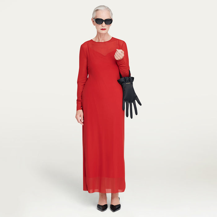 Woman in a red dress holding a black satin hand-shaped handbag against a white background