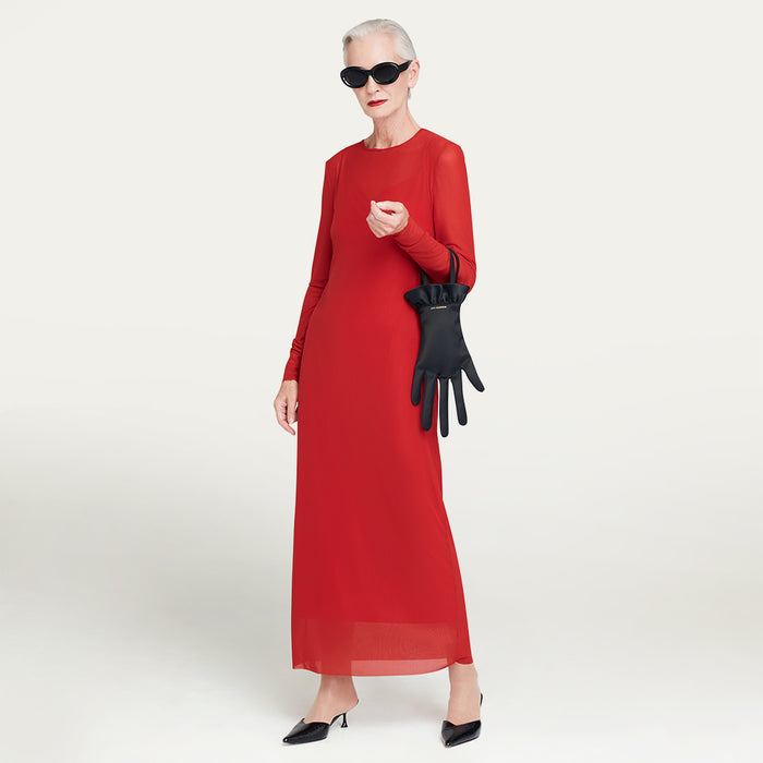 Woman in a red dress holding black satin hand-shaped handbag against a white background