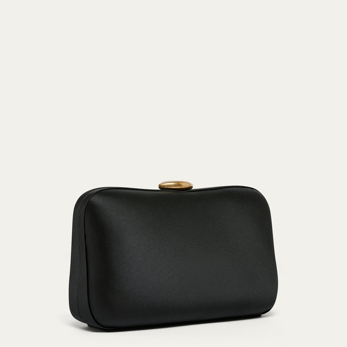 Black satin clutch bag with a gold lip clasp on a light gray background