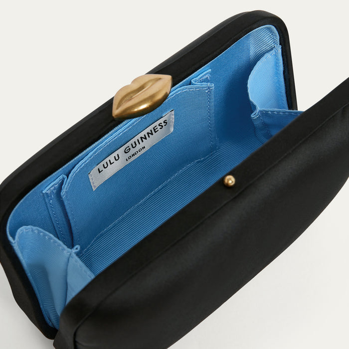 Black satin clutch bag with blue interior and gold lip clasp, featuring Lulu Guinness branding.
