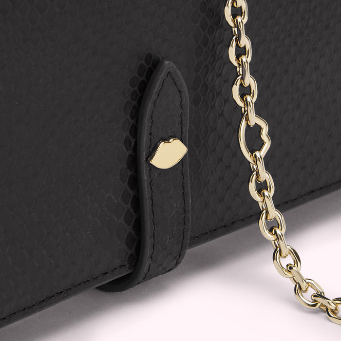Close-up of a black snakeskin-textured wallet with a gold chain and lip-shaped detail.