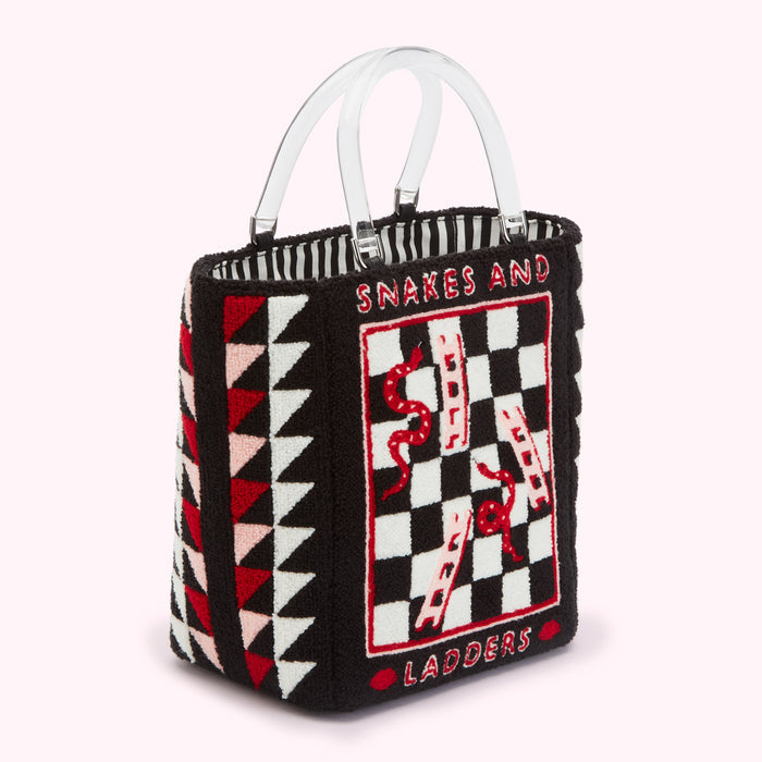Black tote bag with clear handles, featuring an embroidered Snakes and Ladders game board and geometric patterns in red, pink, and white.