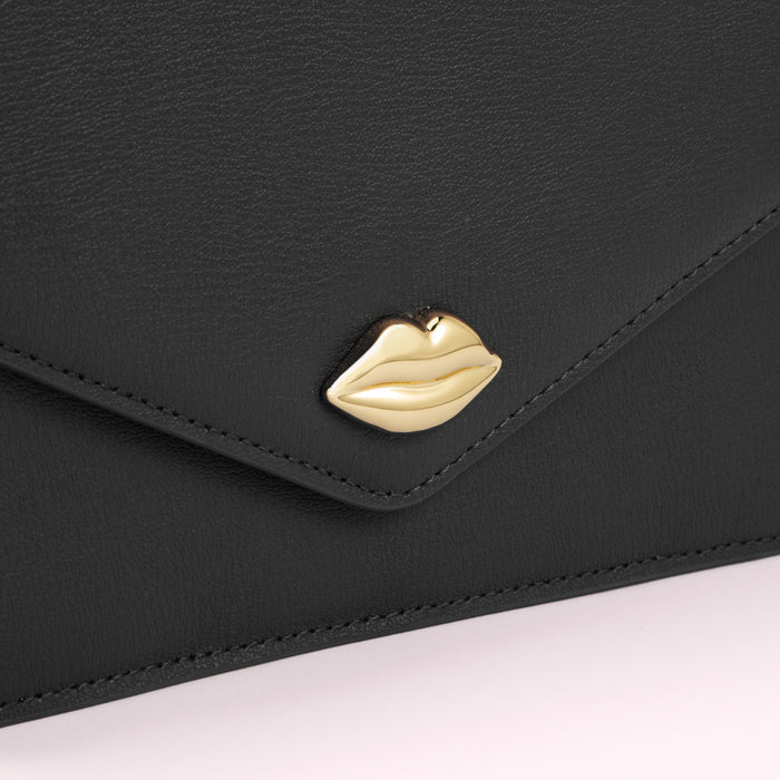 Close-up of a black leather envelope-style bag with a gold lip-shaped clasp.