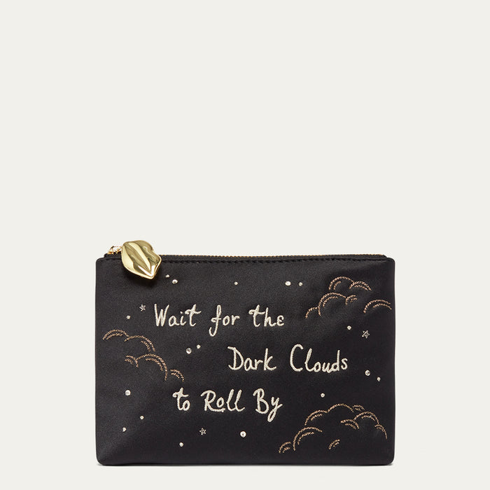 Black satin pouch with gold text and cloud designs on a beige background