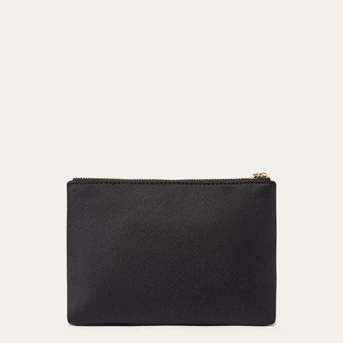 Black satin pouch with a gold zipper on a light beige background