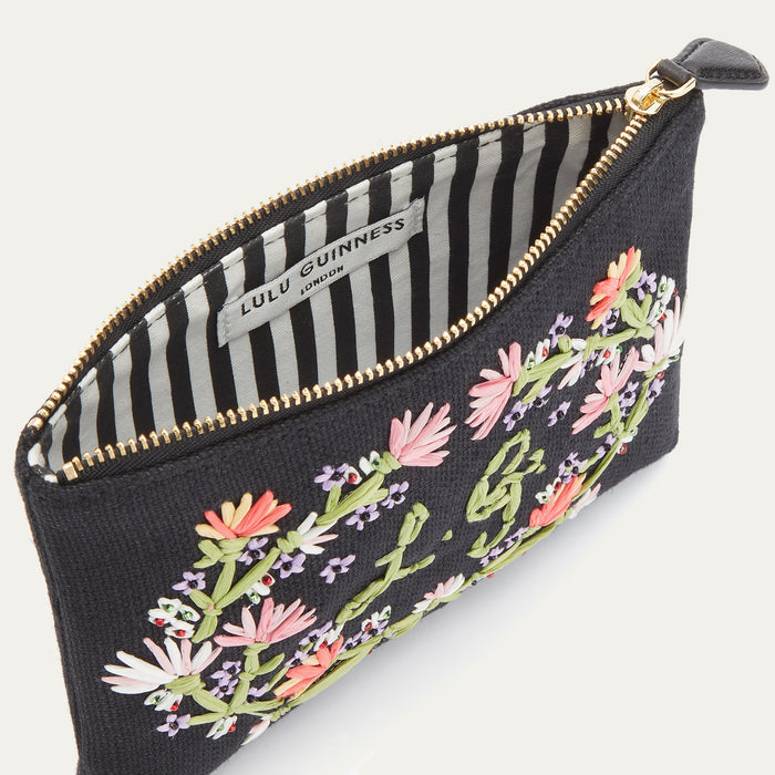 Inside image of a black canvas pouch with pastel floral embroidered detail and embroidered L.G. monogram.