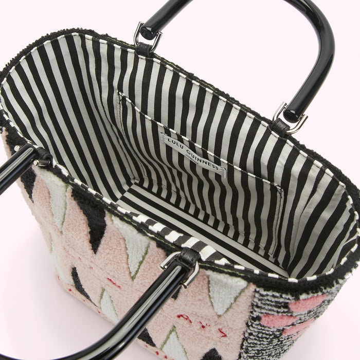 Interior of a Lulu Guinness handbag with a black and white striped lining and pink, black and white textured exterior. The handles are black.