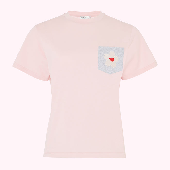 Pink t-shirt with a grey pocket and a flower appliqué©.