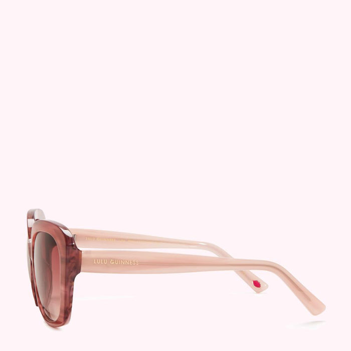 Side view of Lulu Guinness sunglasses with a blush pink frame and tortoiseshell-patterned lenses.
