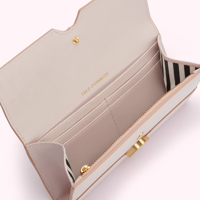 Open blush pink Lulu Guinness wallet with gold zipper and hardware. The interior features multiple card slots and a black and white striped fabric detail.
