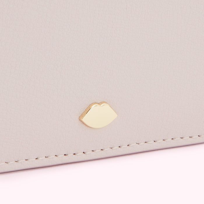 Close-up of a pale pink leather purse with a gold lip-shaped emblem.