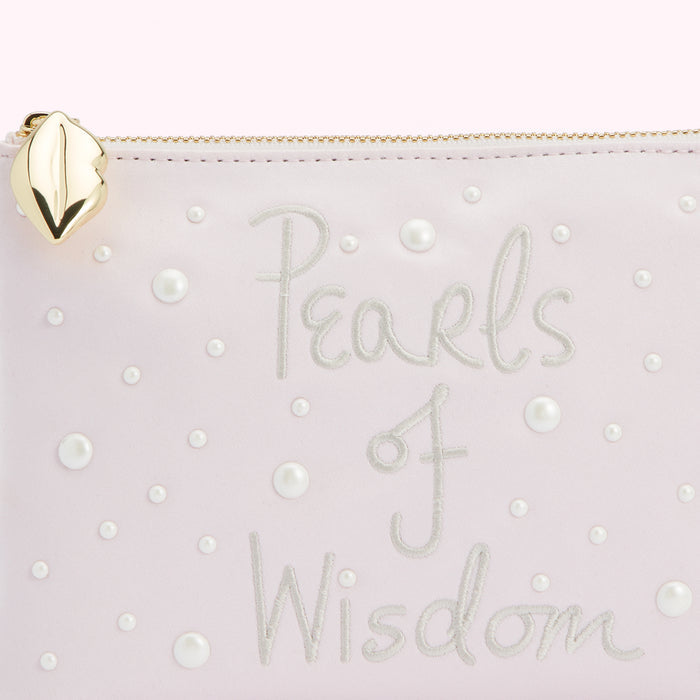 Close-up of a pale pink pouch with the words "Pearls of Wisdom" embroidered on it and embellished with small pearl beads.