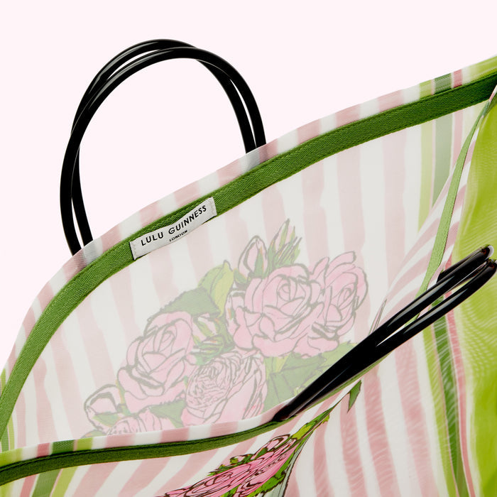 Inside of a Lulu Guinness London tote bag. The bag is pale pink and green striped mesh with a green trim and a pink rose print. The black handles are visible.