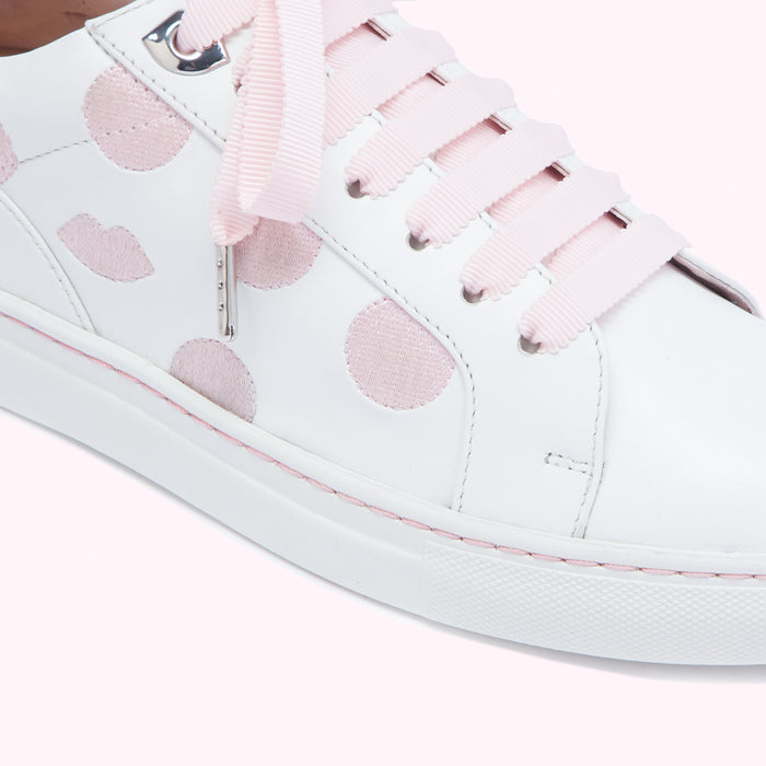 Close-up of white leather sneakers with pink polka dots and pink laces.