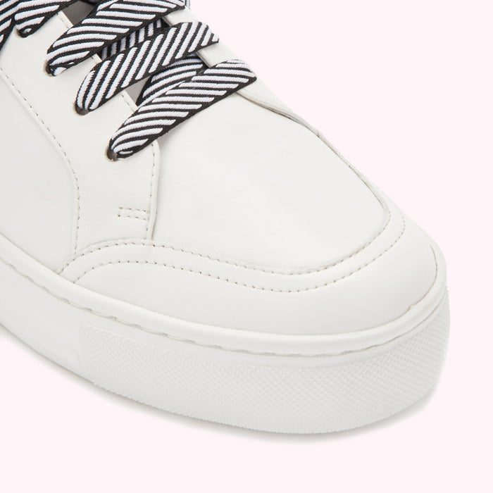 Close-up of a white leather sneaker with black and white striped laces.