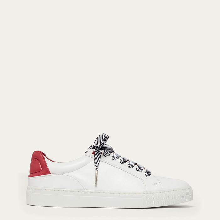 White sneaker with red heel and black and white striped laces on a white background