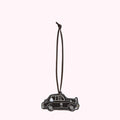 Black leather luggage tag shaped like a London cab, hanging from a brown cord.