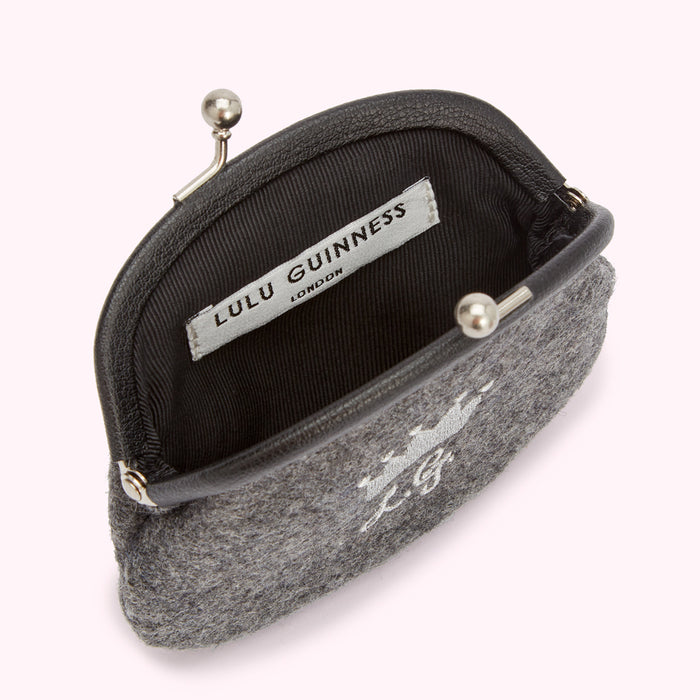 Grey Lulu Guinness purse with a crown and LG logo embroidered on the front, open to reveal a black fabric interior with the brand's label.
