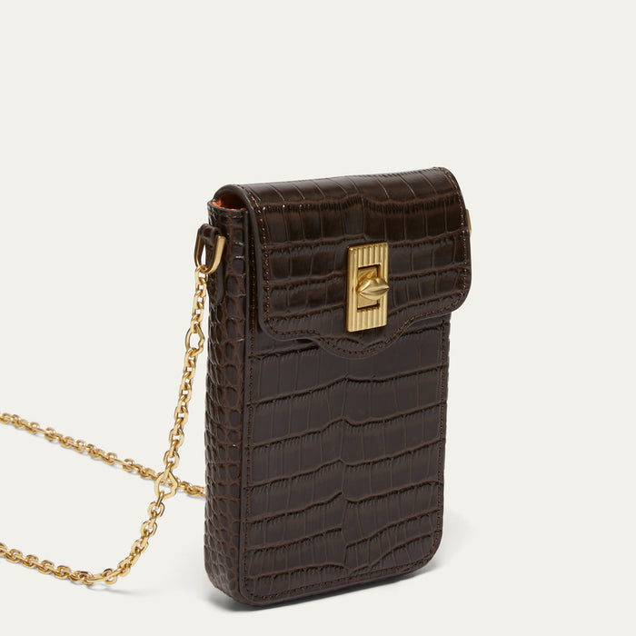 A dark brown croc effect embossed leather crossbody phone pouch with a gold-tone turn-lock clasp and a gold chain strap, shown on a light off-white background.