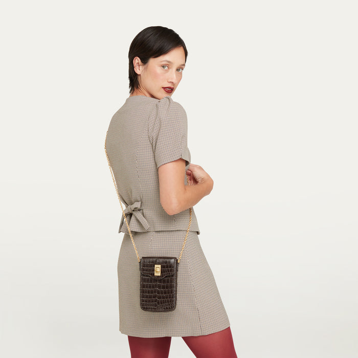 Women wearing a tweed jacket and skirt with burgundy tights with a croc-effect embossed leather crossbody bag.