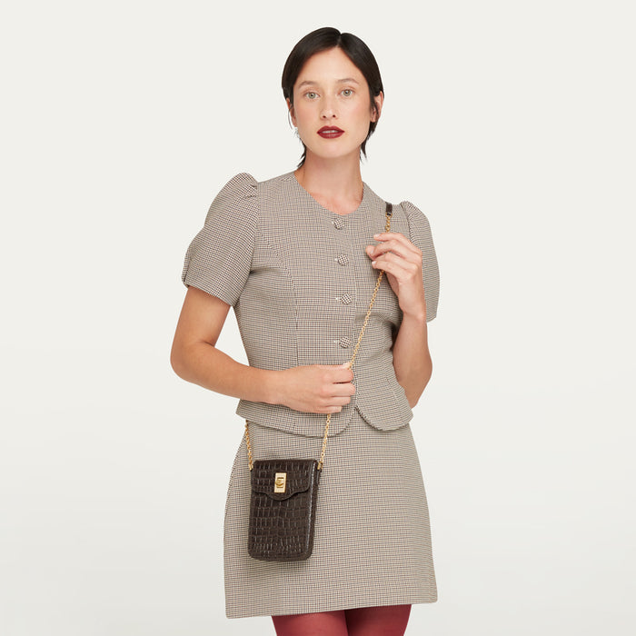 Women wearing a tweed jacket and skirt with burgundy tights with a croc-effect embossed leather crossbody bag.